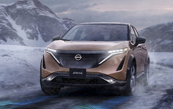 Nissan ARIYA in Sunrise Copper on snowy mountain road | Pischke Motors Nissan in La Crosse WI